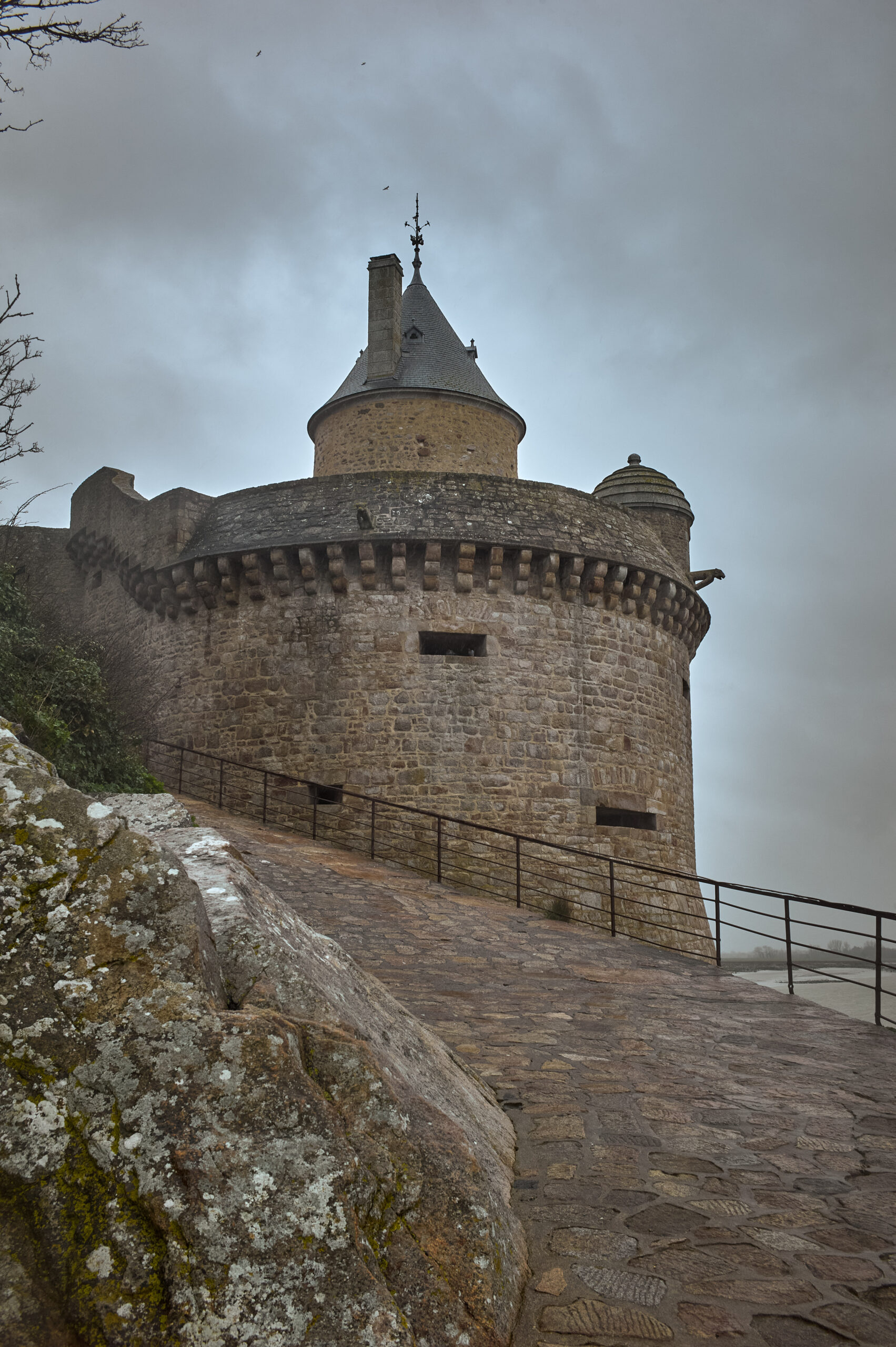 Tour en pierre médiévale sous ciel nuageux.